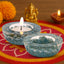 Two blue stone candle holders with candles on a colorful mat with decorative elements.