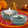 Two blue stone candle holders with candles on a colorful mat with decorative elements.