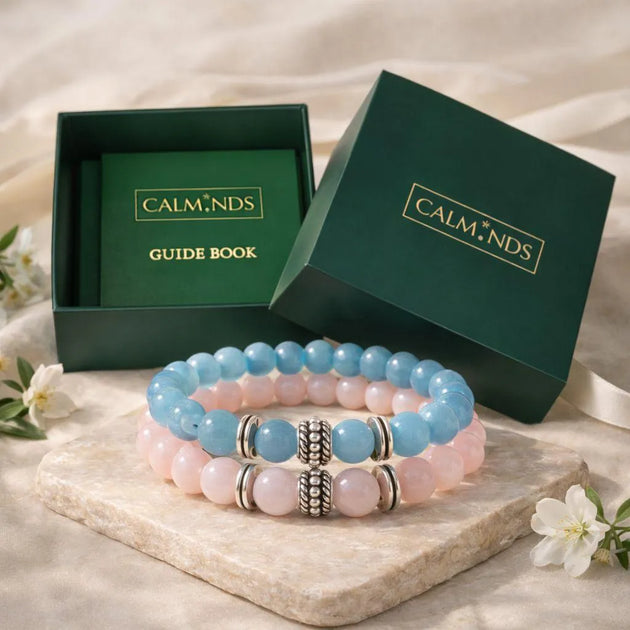 Set of pink and blue beaded bracelets with 'CALM.NDS' packaging on a light background