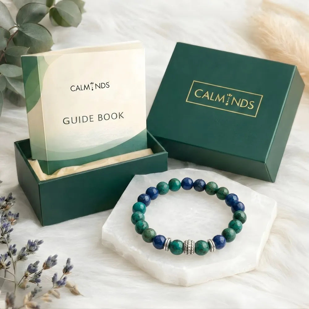Green and blue beaded bracelet with 'Calminds' packaging and guide book on a white surface.