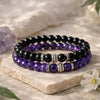 Stack of black and purple beaded bracelets on a stone surface with a soft background