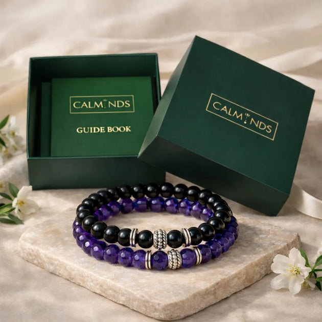 Two beaded bracelets on a stone surface with 'CALM NDS' branded boxes in the background.