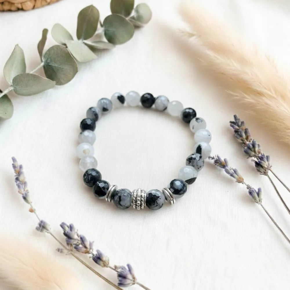 Beaded bracelet on a light surface with eucalyptus and lavender.