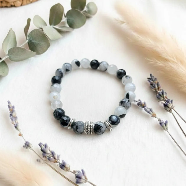 Beaded bracelet on a light surface with eucalyptus and lavender.