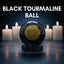 Black tourmaline ball with a gold symbol in front of lit candles on a dark background
