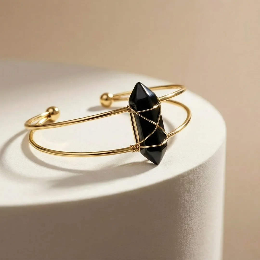 Gold bracelet with a black gemstone on a beige background