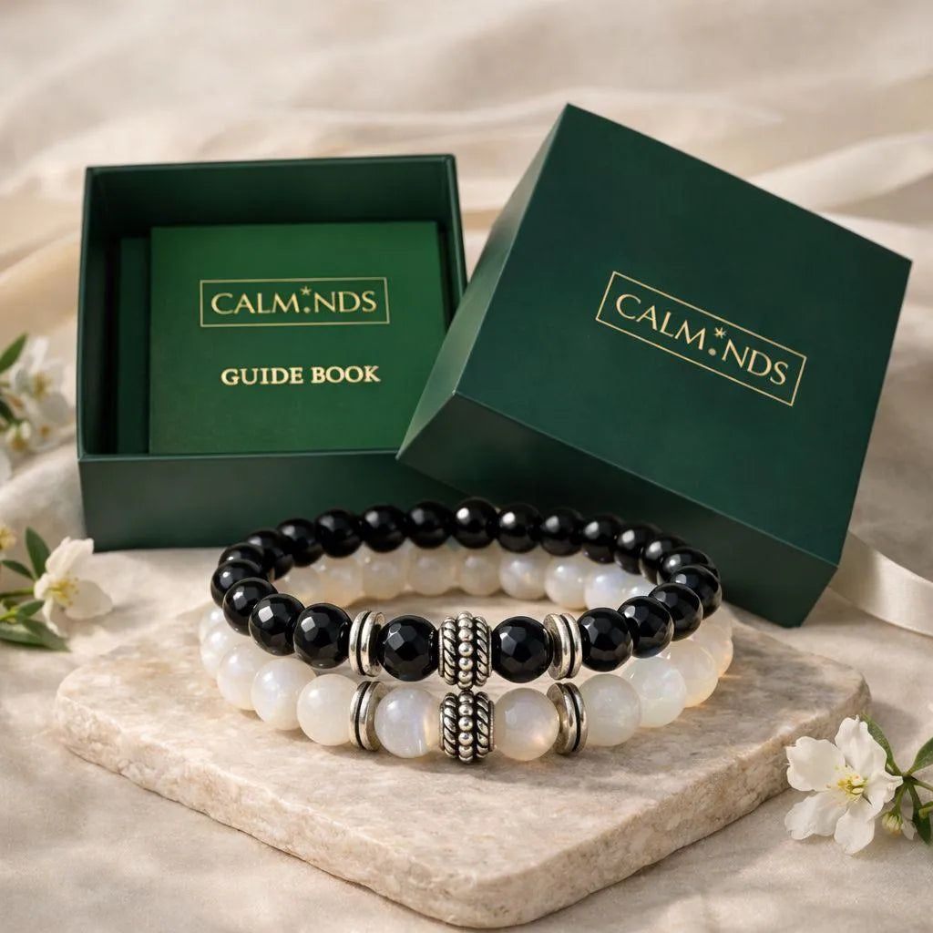 Set of black and white beaded bracelets with 'CALM.NDS' packaging on a light background