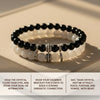 Black and white beaded bracelet with silver accents on a beige surface, accompanied by usage instructions.