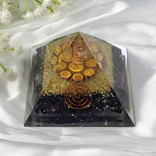 Black Pyramid object with spiral designs on a white fabric background