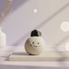 Ceramic ball with a smiling face and a small black tourmaline rock on top, set against a soft, blurred background.