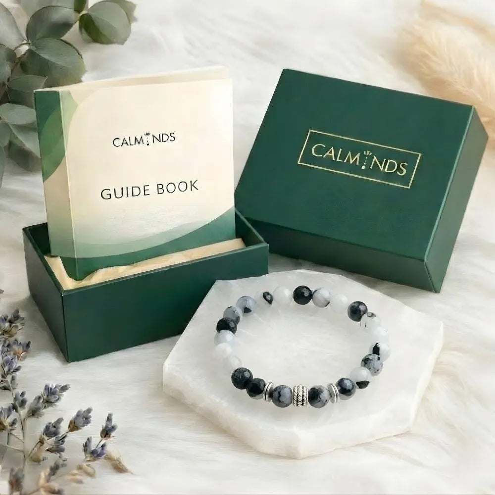 Calminds bracelet and guide book set on a white surface with greenery