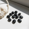 Black stones arranged on a light surface with a beige cloth beside them