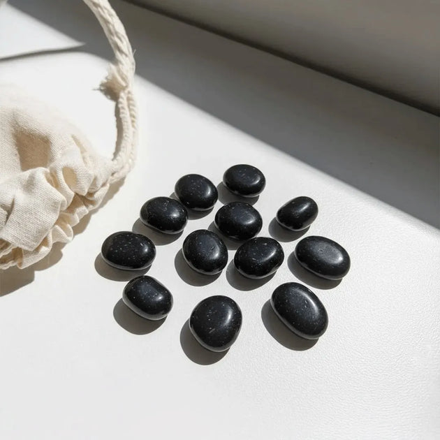 Black stones arranged on a light surface with a beige cloth beside them