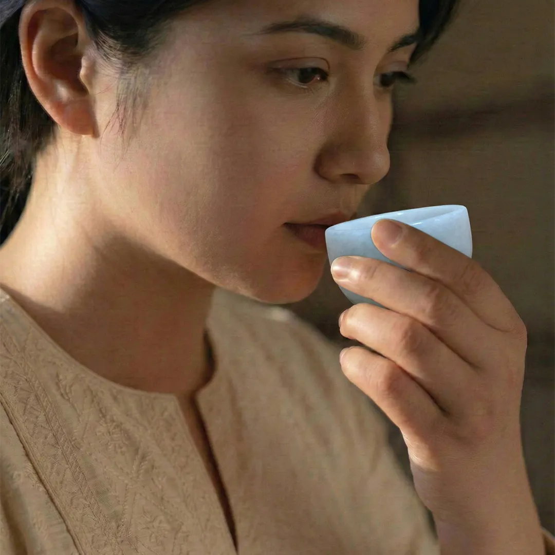 Woman holding a small white container to her mouth against a blurred background