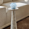 Marble side table with a decorative blue crystal piece on top, next to a beige sofa.