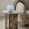 Marble side table with a decorative blue crystal piece next to a beige sofa.