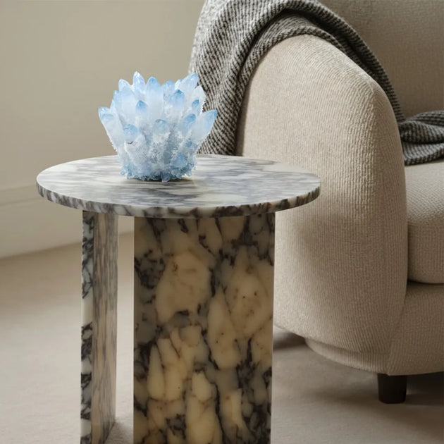 Marble side table with a decorative blue crystal piece next to a beige sofa.