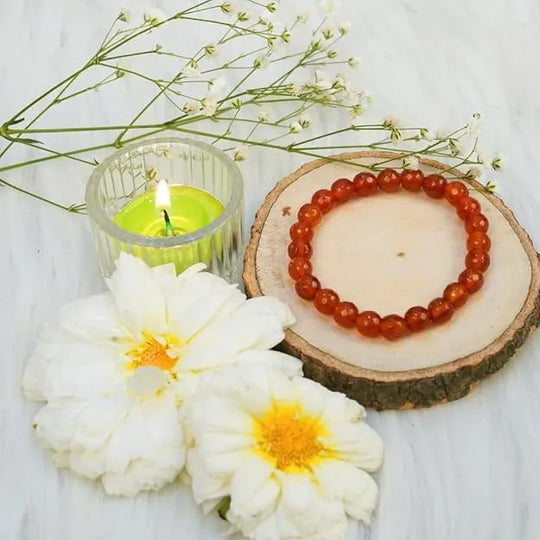 Bracelet on a wooden slice with flowers and a candle on a light background