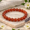 Carnelian beaded bracelet on a stone surface with flowers