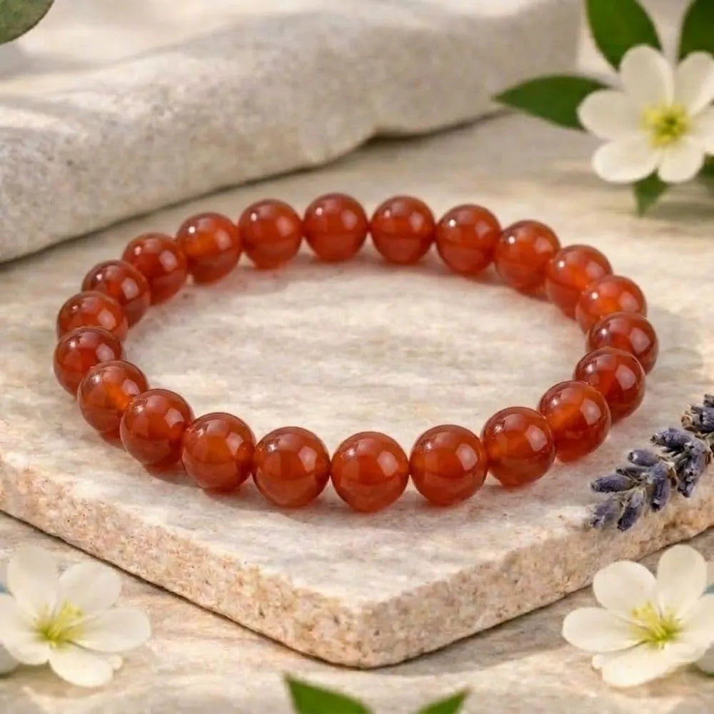 Carnelian beaded bracelet on a stone surface with flowers