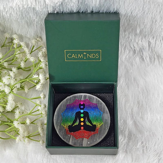 decorative item with a rainbow-colored meditation figure in a calminds box on a white fur background.