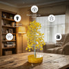 Decorative yellow tree on a wooden table with positive energy benefits text in a cozy room.