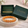 Orange beaded bracelet on a white stand with 'CALMINDS' branded box in the background.