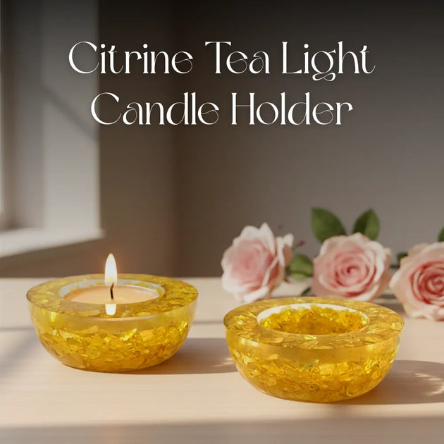 Citrine tea light candle holder with a lit candle on a surface with flowers in the background.