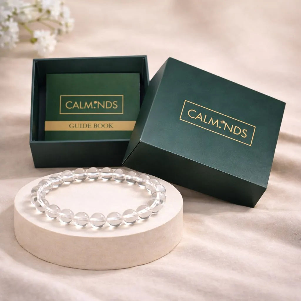 Clear beaded bracelet on a white stand with 'CALMINDS' branded box in the background.