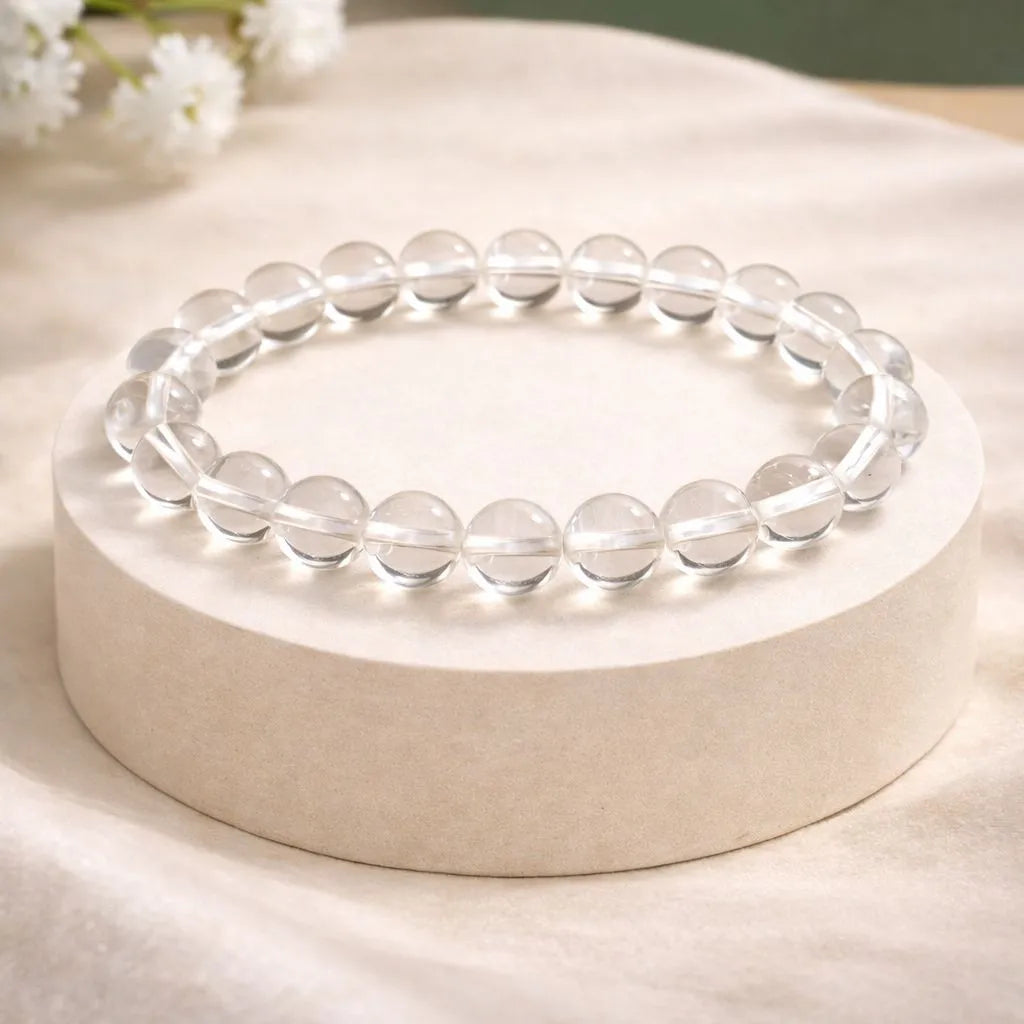 Clear beaded bracelet on a white round base with a soft background