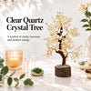 Clear quartz crystal tree on a marble table with a lit candle and small crystal points