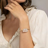 Woman wearing a bracelet with a clear stone on a neutral background