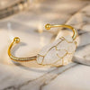 Gold bracelet with a clear stone on a marble surface