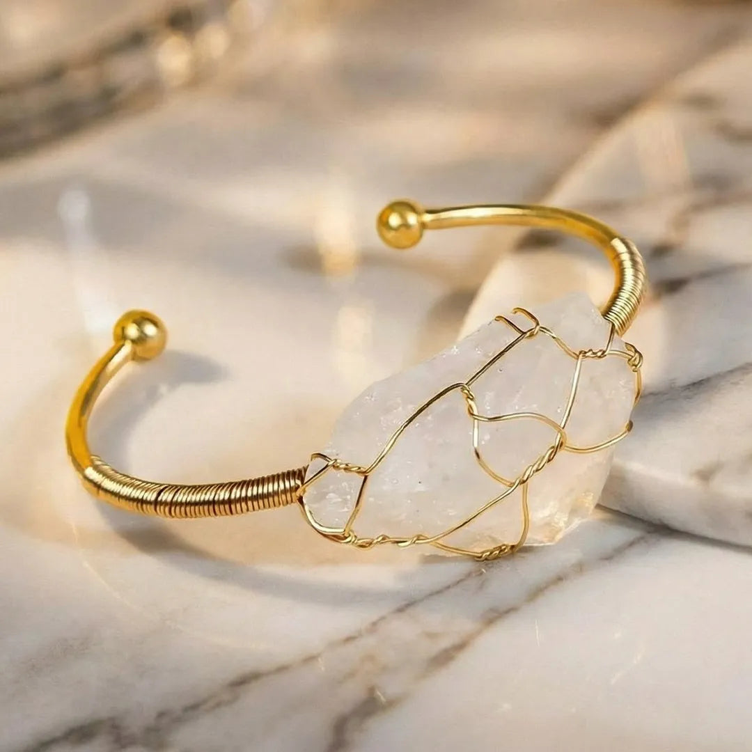 Gold bracelet with a clear stone on a marble surface