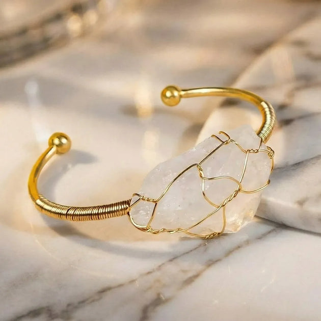 Gold bracelet with a clear stone on a marble surface