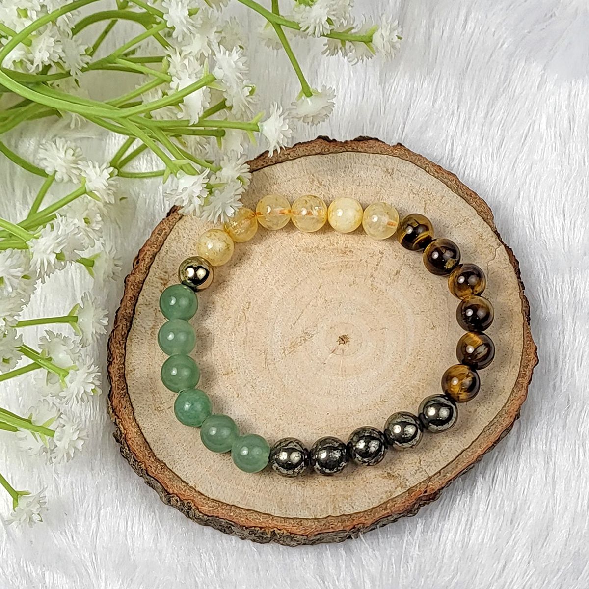 Set of beaded bracelets on a wooden slice with flowers in the background | Crystal money bracelet