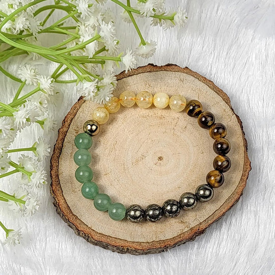Set of beaded bracelets on a wooden slice with flowers in the background | Crystal money bracelet