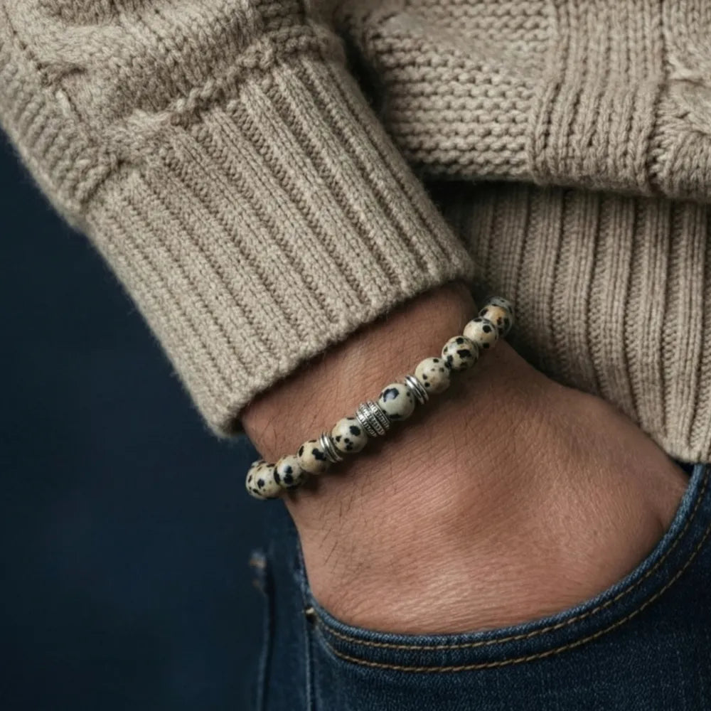 Close-up of a hand wearing a beaded bracelet with a dark background