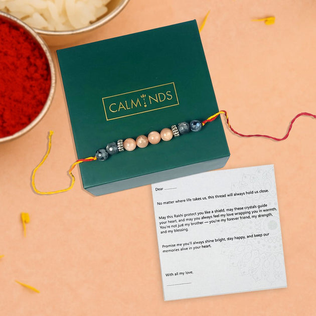 Crystal rakhi with a green box labeled 'Calminds' on a peach background