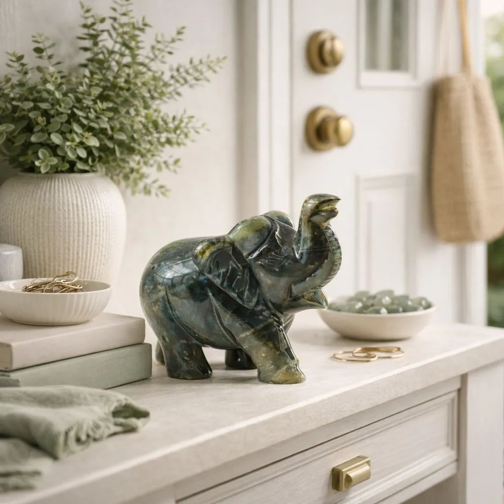 Decorative green elephant figurine on a white surface with a plant and books in the background.