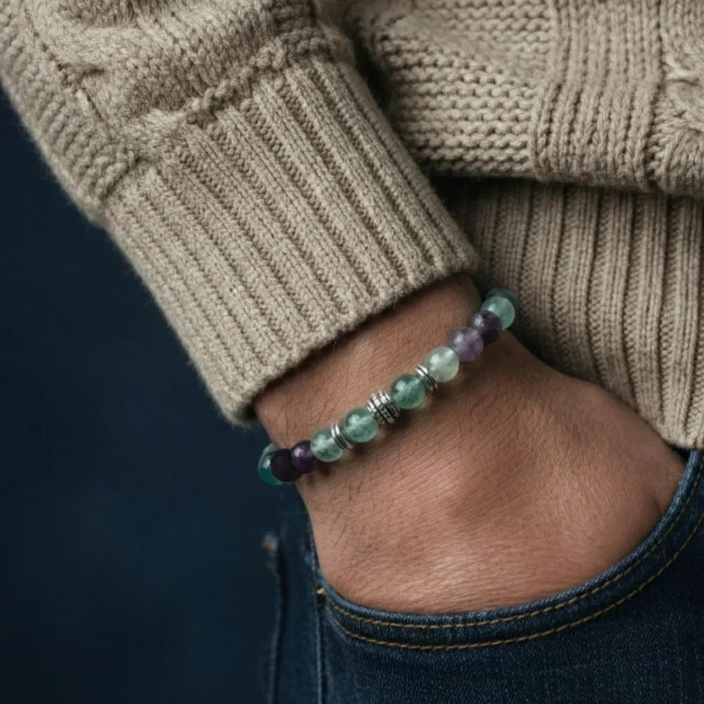 Close-up of a hand wearing a beaded bracelet with a neutral background