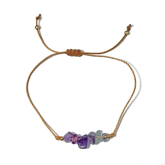 thread bracelet with purple and green beads on a white background