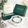 Calminds bracelet and guide book set on a white surface with greenery