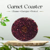Garnet coaster with a brand logo on a wooden stand, surrounded by greenery.