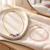 Gold chain necklace with amethyst chips and a rose quartz bead anklet on a ceramic tray