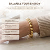 Gold bracelet worn on a wrist with text about its benefits on a light background