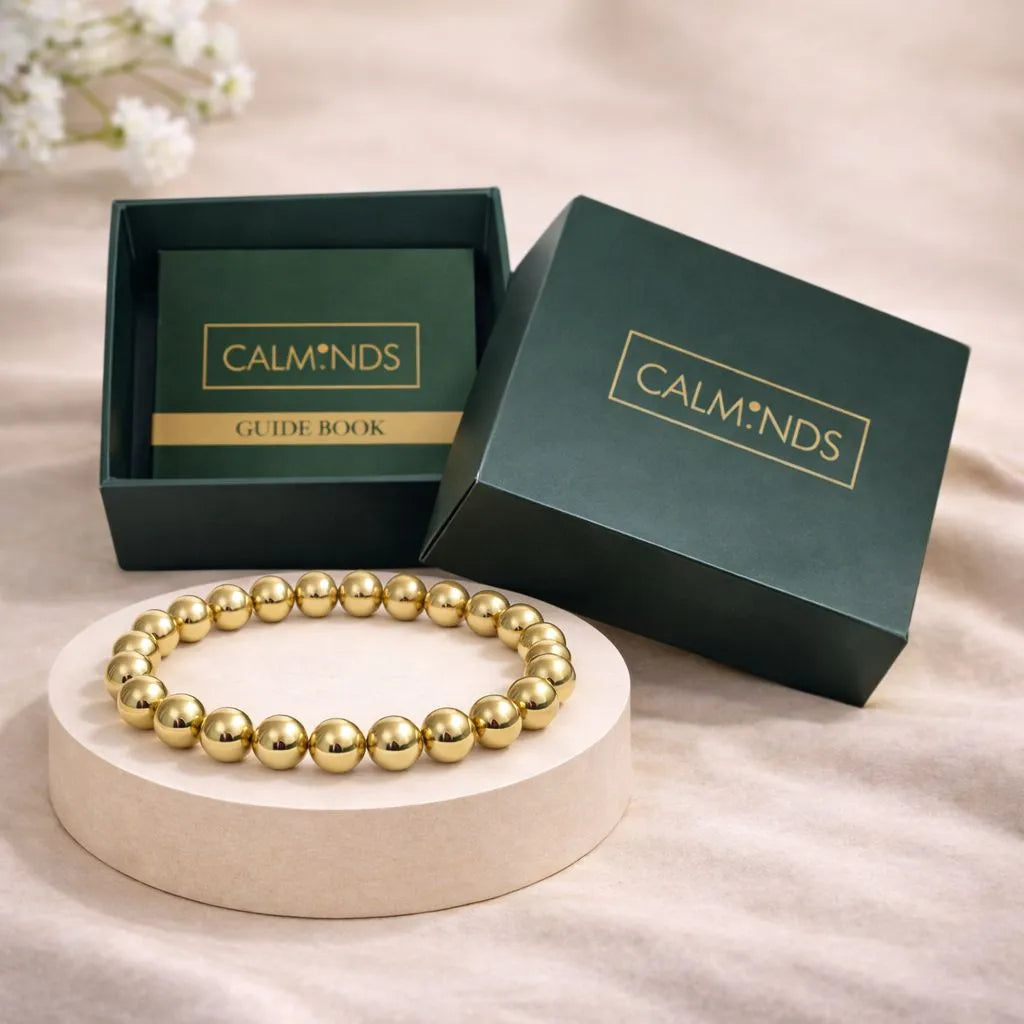 Gold beaded bracelet on a white stand with Calminds packaging in the background