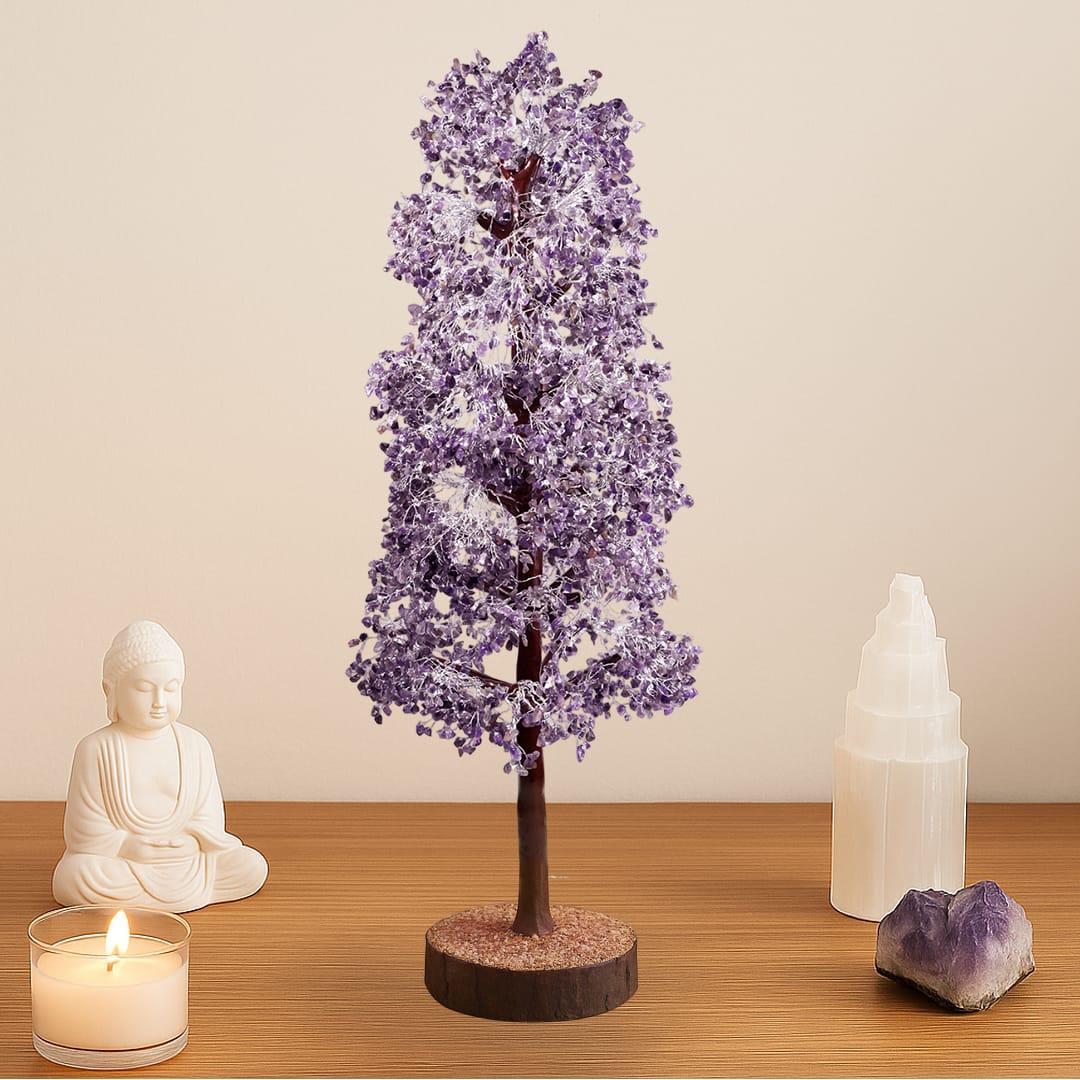 Decorative purple tree with a candle, statue, and crystal on a wooden surface.