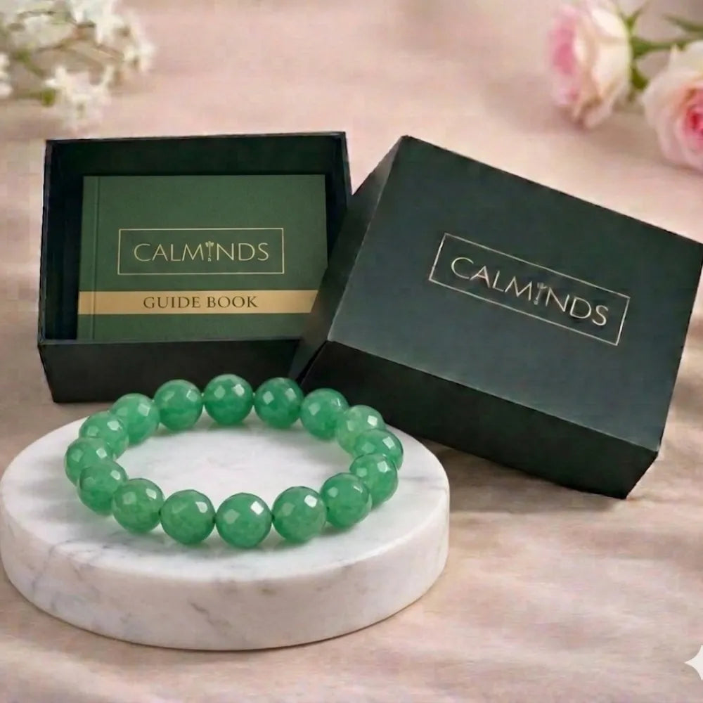 Green beaded bracelet on a marble stand with 'CALMINDS' branded box in the background.