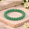 Green beaded bracelet on a wooden surface with flowers